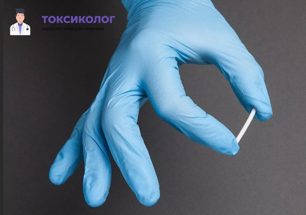 Подготовка стерильного импланта-капсулы для процедуры вшивания ампулы. Врач в голубой перчатке держит препарат.